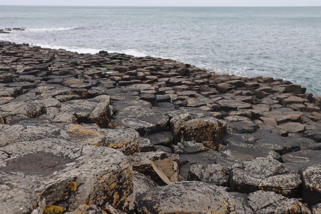 a rocky beach with a body of water in the background