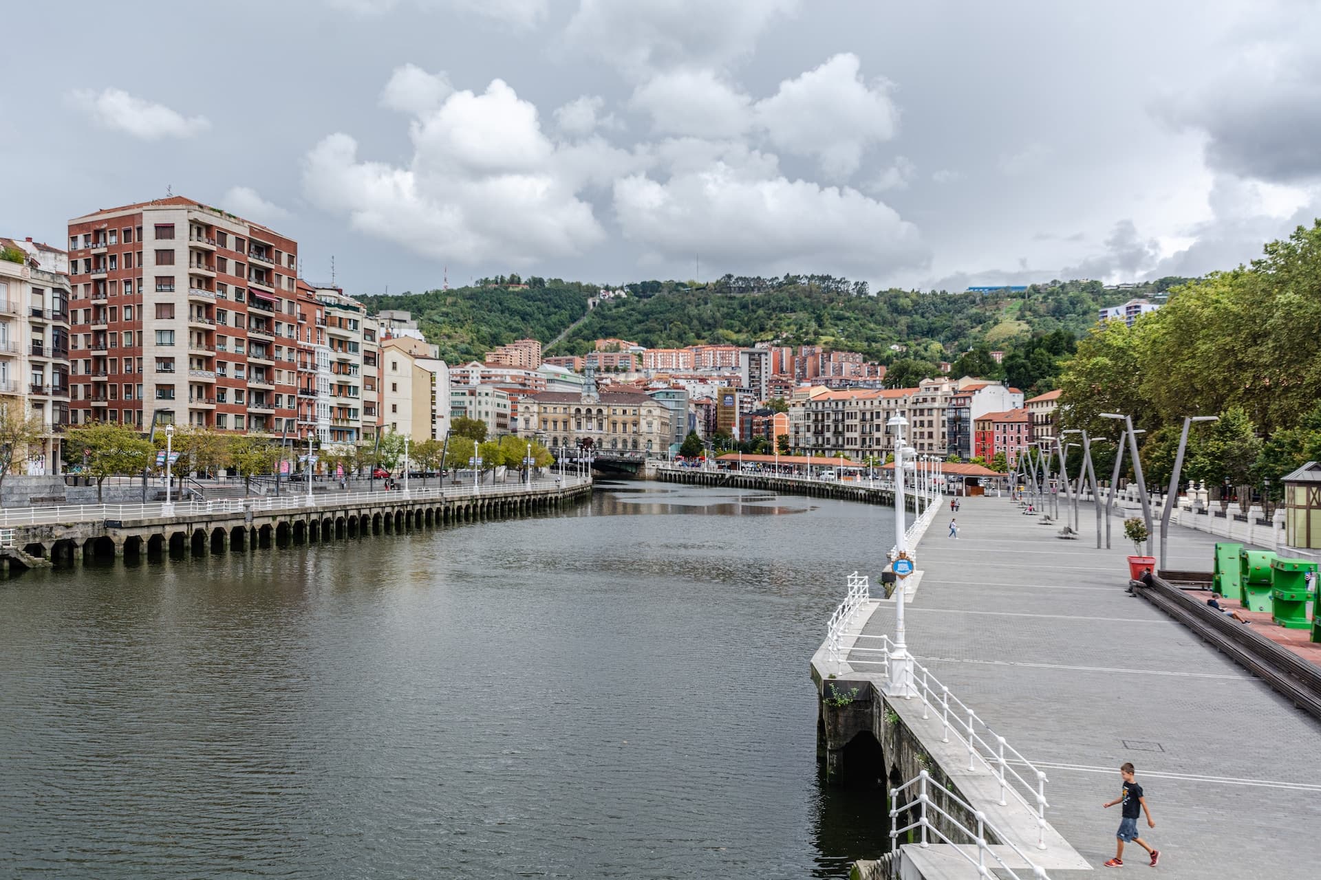 people walking on the bridge over the river during the day