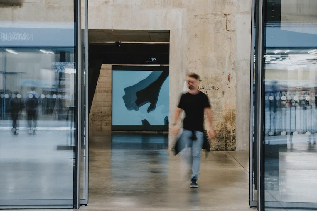 a man walking past a building with a large screen