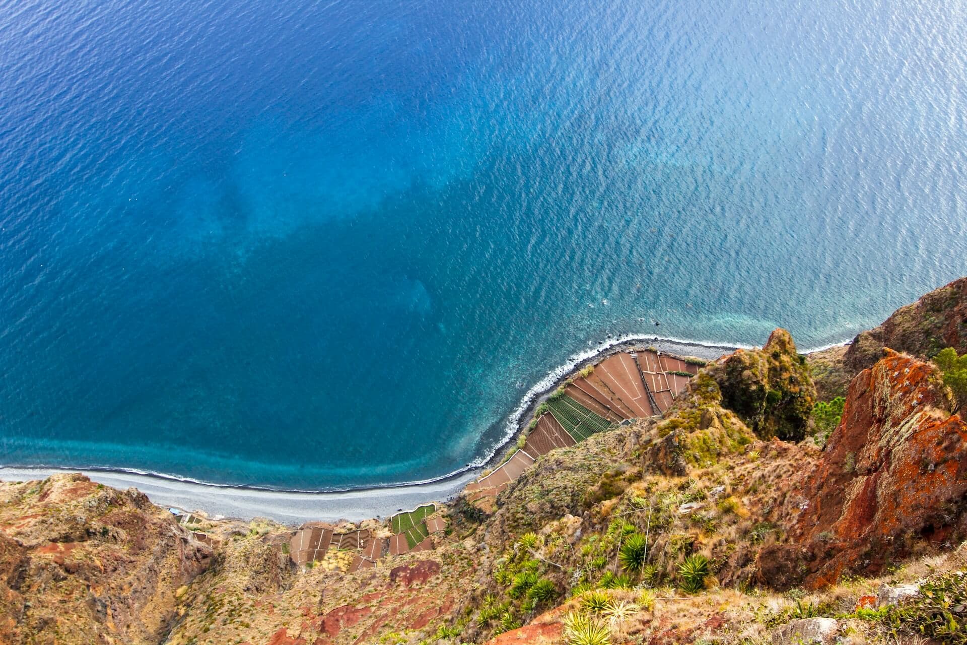 aerial view of green and brown mountain beside blue sea under blue sky during daytime