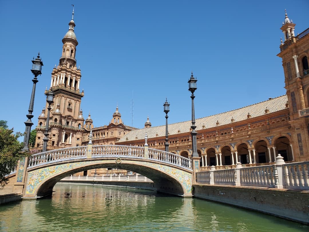 brown concrete bridge over river under blue sky during daytime