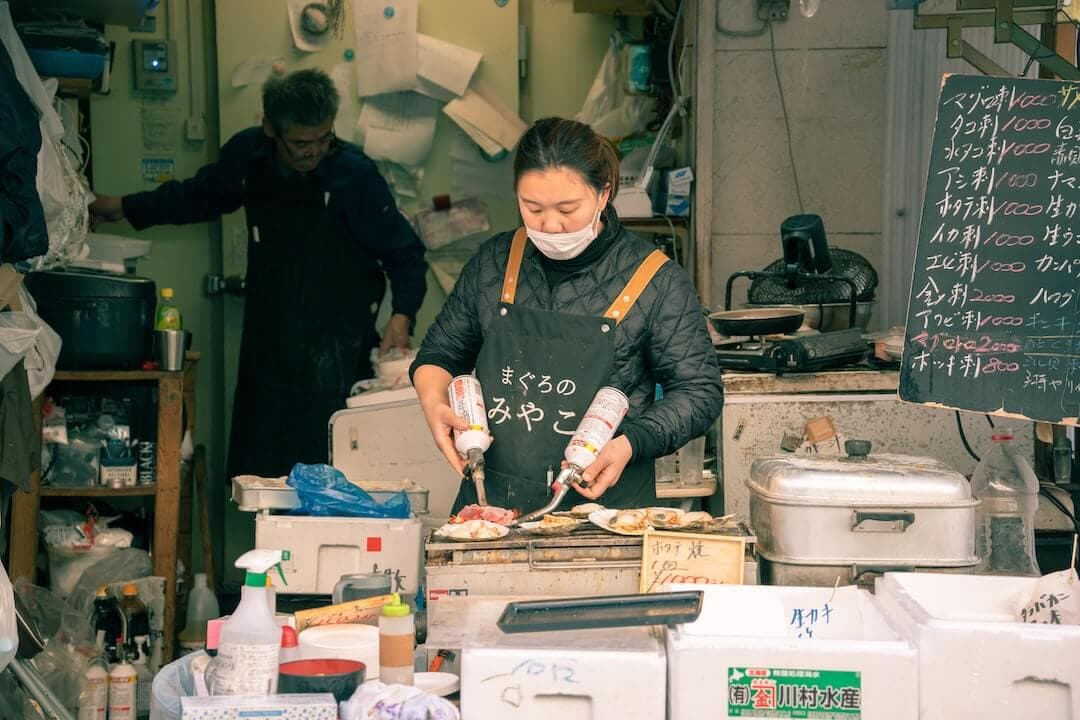 a woman wearing a face mask preparing food in a kitchen