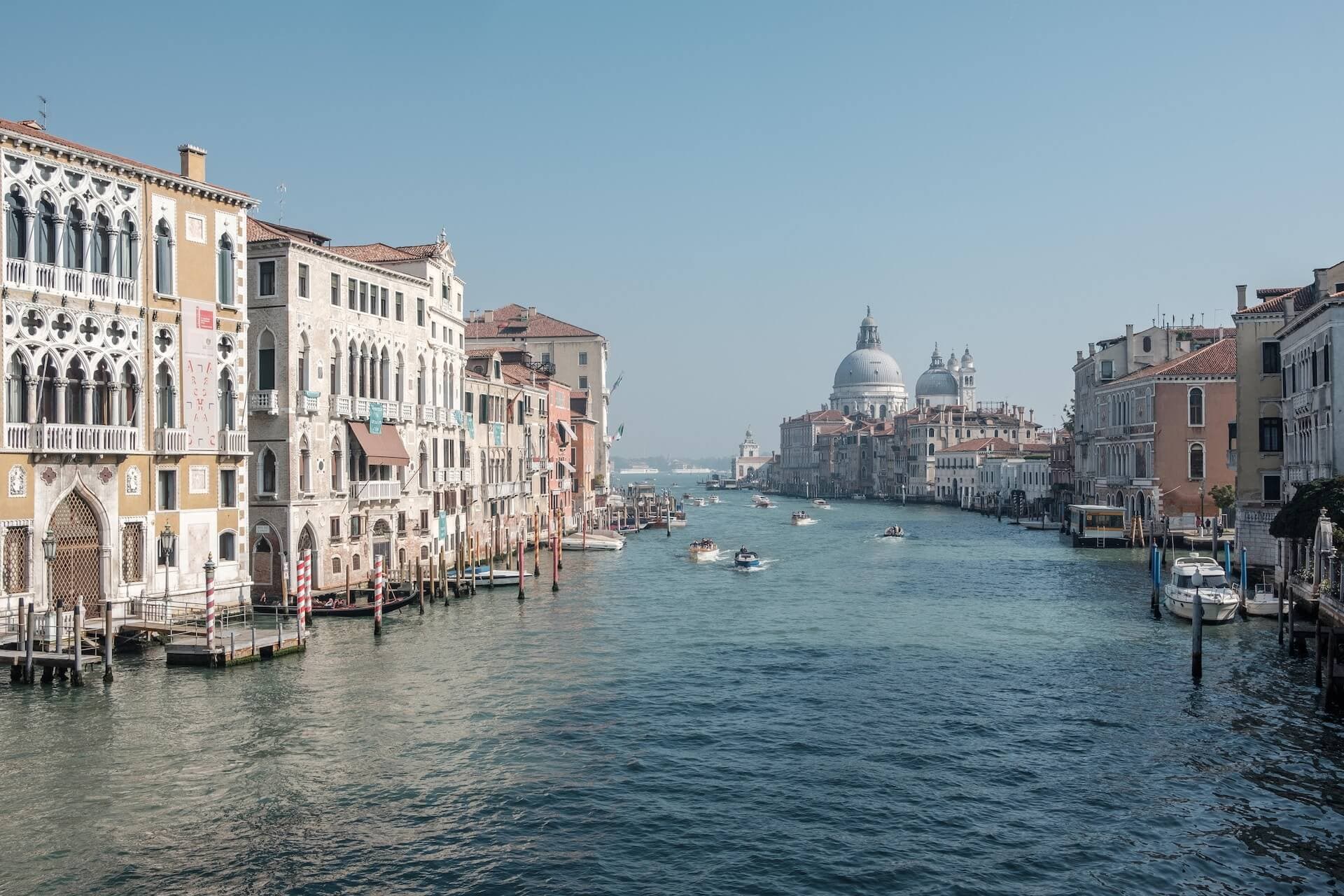 boats sailing through the sea between buildings